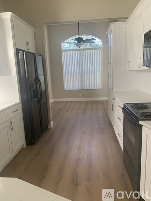 A kitchen with white cabinets and a black fridge.
