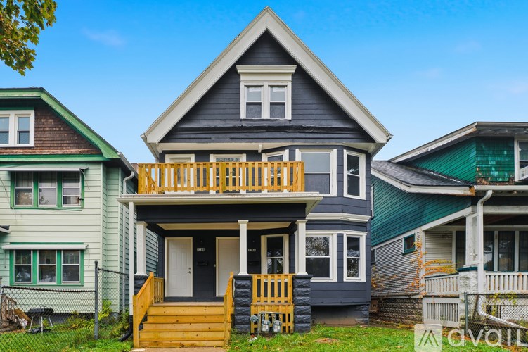 A house with a blue roof and a white door is in front of two other houses.