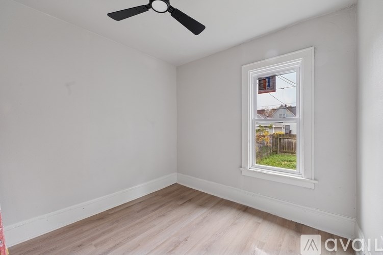 A room with a window showing a view of a fence and houses.