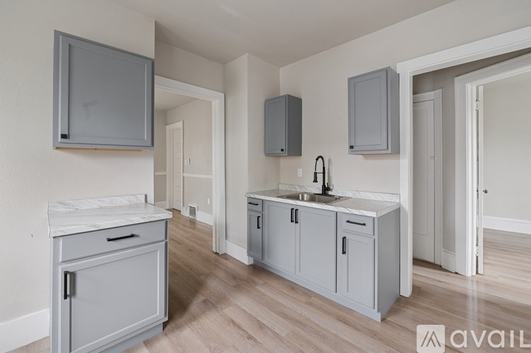 A kitchen with a sink, cabinets, and a microwave.