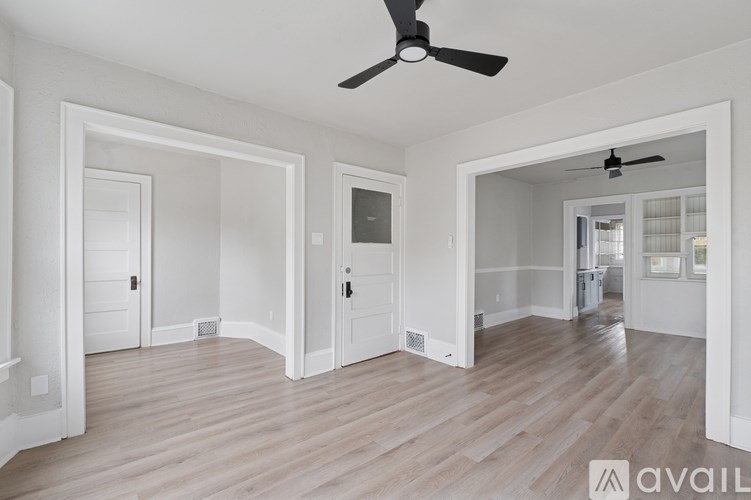 A spacious room with a ceiling fan and wooden flooring.