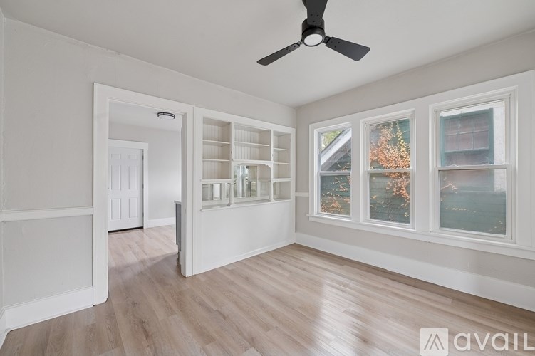 A room with a ceiling fan and a window overlooking a body of water.