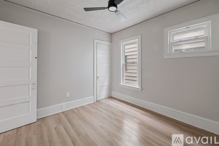 A room with a ceiling fan and two doors.
