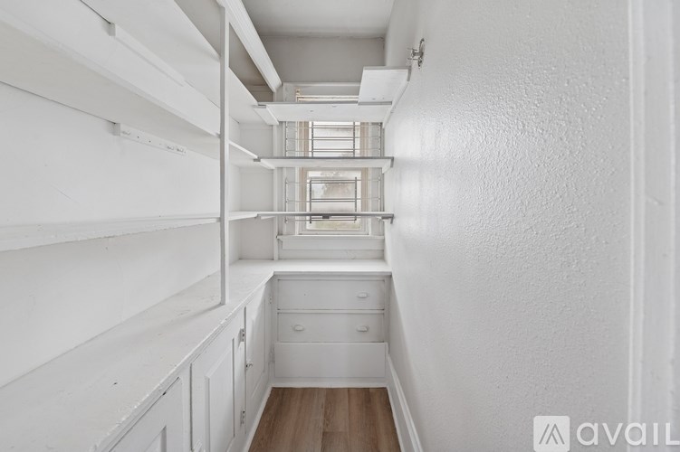 A white kitchen with a drawer and a window.