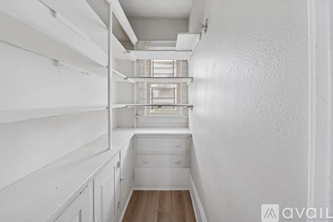 A white kitchen with a drawer and a window.