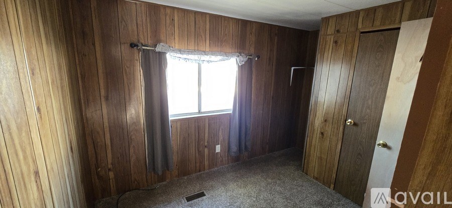 A room with wooden walls and a window with a curtain.