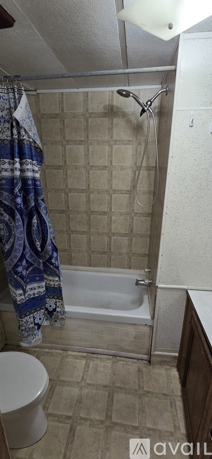A bathroom with a toilet, a shower with a blue towel hanging on the side, and a white ceiling.
