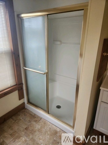 A bathroom with a glass shower door and tiled floor.