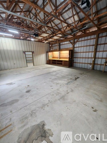 A large, empty room with wooden beams on the ceiling and a concrete floor.