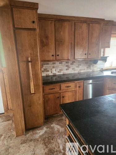A kitchen with wooden cabinets and a black countertop.