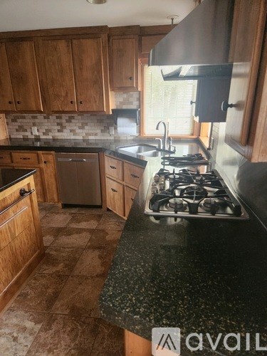 A kitchen with a black granite countertop and wooden cabinets.