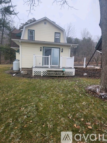 A house with a white porch and a tree in front.