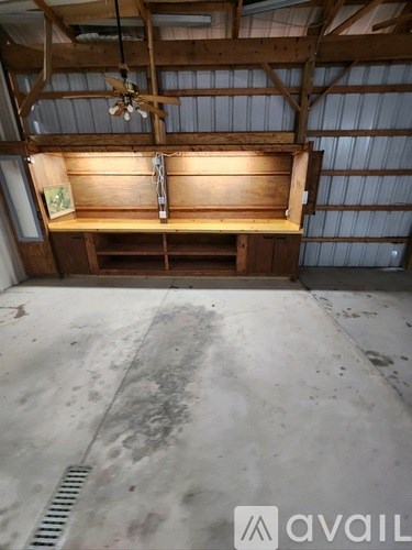 A wooden bench with a fan above it in a room with a concrete floor.