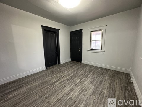 A room with a wooden floor and two doors.