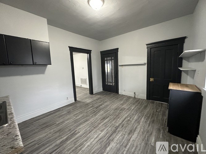 A room with black cabinets and a wooden floor.