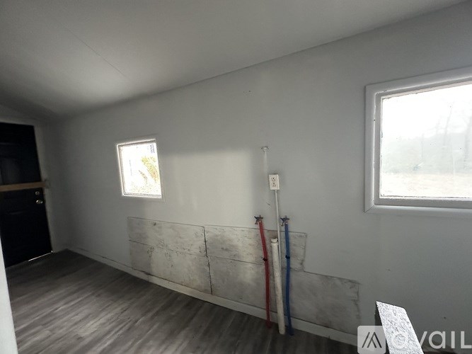 A room with a window and a wall with pipes and wires.