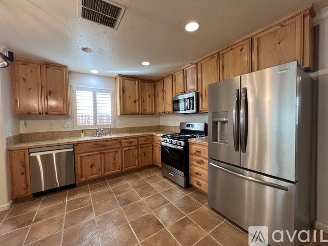A kitchen with wooden cabinets and a stainless steel refrigerator.