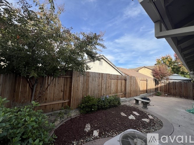 A backyard with a wooden fence and a bench.