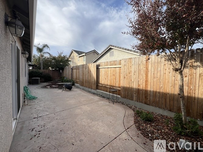 A backyard with a wooden fence and a tree.