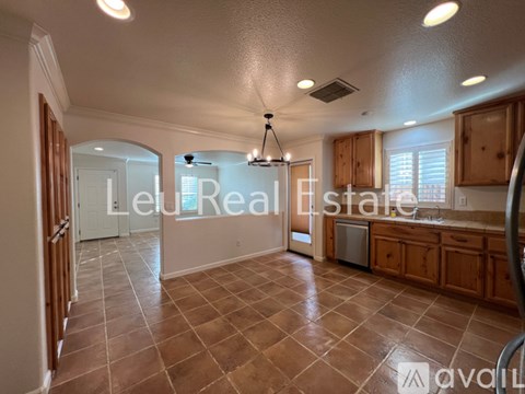 A spacious kitchen with wooden cabinets and a tile floor.