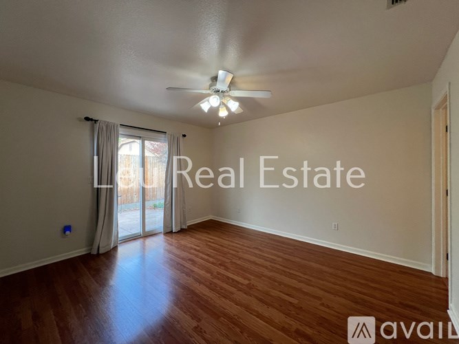 A spacious room with wooden flooring and a sliding glass door leading outside.