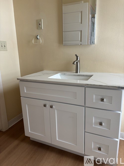 A white bathroom vanity with a sink and a mirror above it.