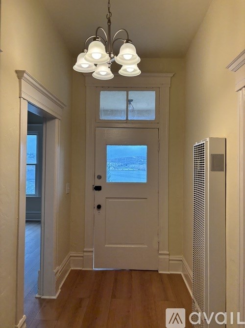 A white door with a window above it in a hallway.