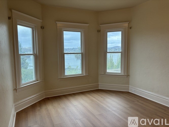 A room with two windows and wooden floors is available for rent.