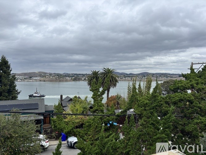 A view of a cloudy sky over a body of water with a boat and buildings in the distance.