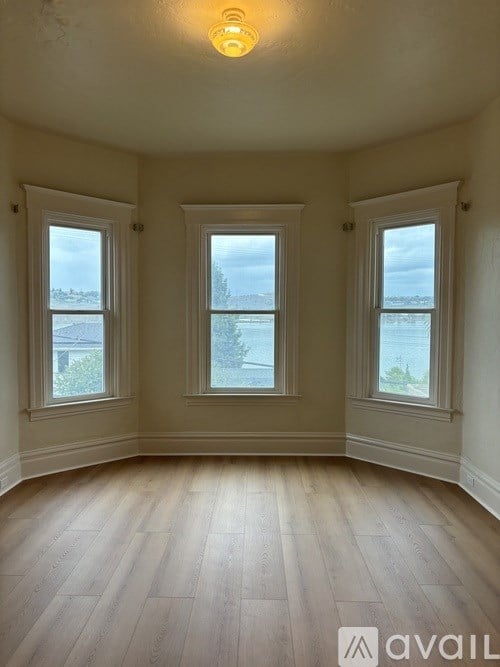 A room with wooden floors and three windows.