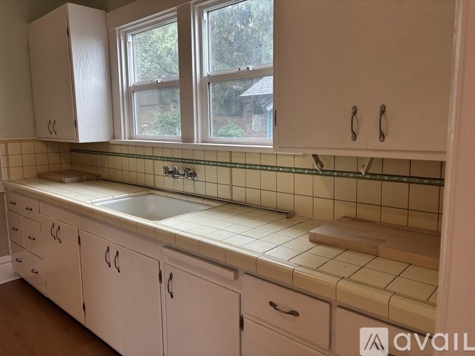 A kitchen with white cabinets and a green tile backsplash.