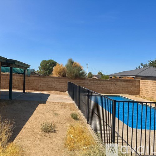A pool surrounded by a black fence and a concrete patio.