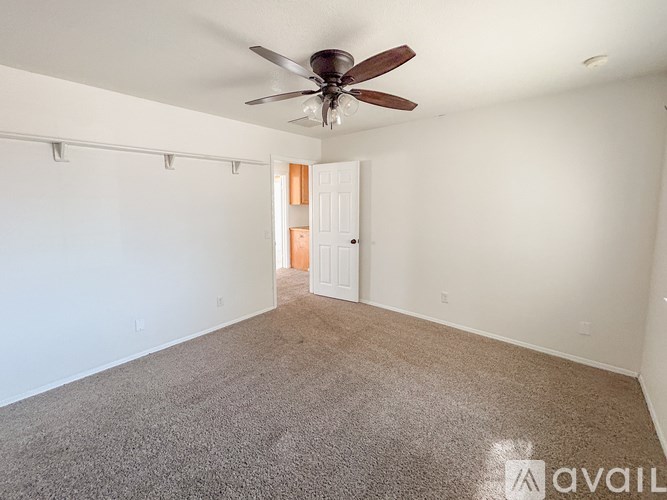 A room with a ceiling fan and carpeted floor.