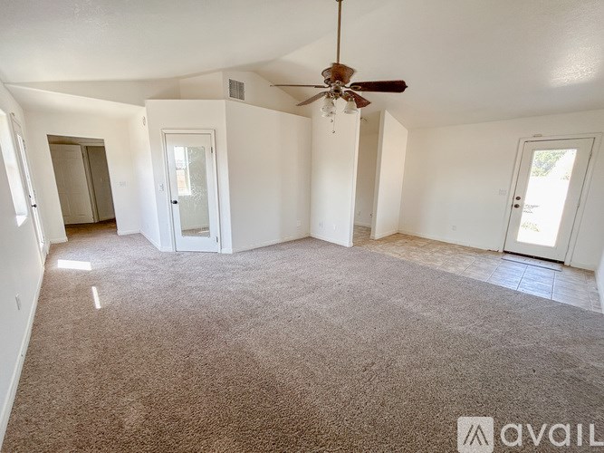 A spacious room with a ceiling fan and carpeted floor.