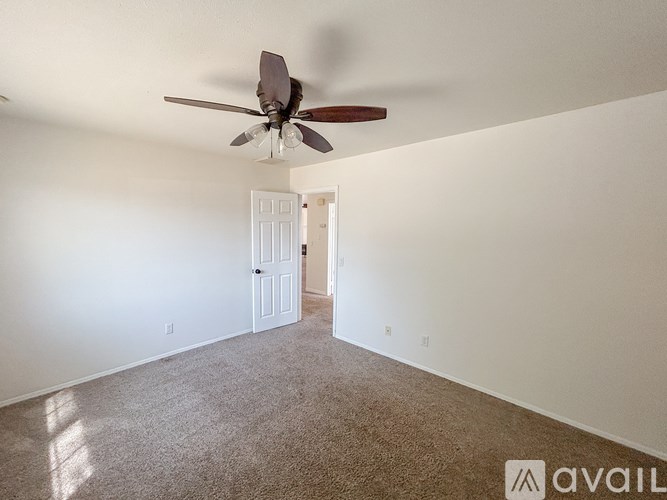 A room with a ceiling fan and a door leading to another room.