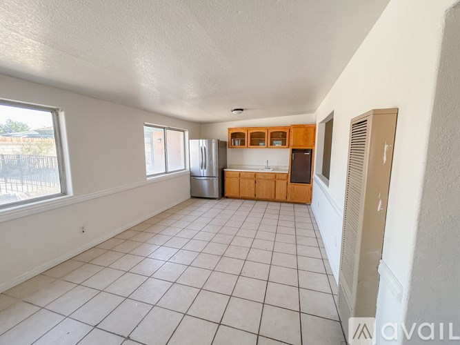 A kitchen area with white tiled floors and wooden cabinets.