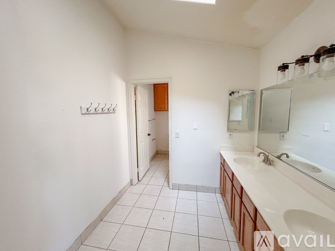 A bathroom with a white tiled floor and a white sink.