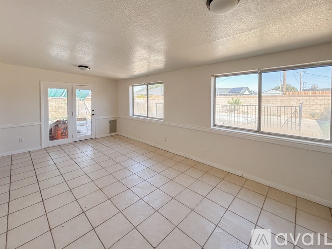 A spacious room with tiled flooring and large windows.