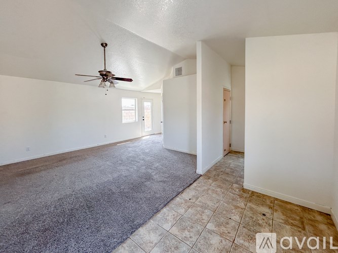 A spacious room with a ceiling fan and a rug on the floor.