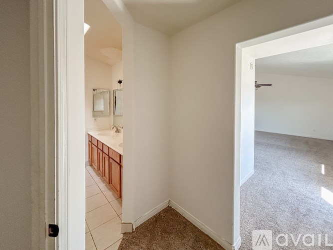 A white room with a carpeted floor and a bathroom visible through the door.