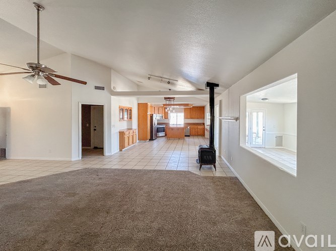 A spacious living room with a fan and a suitcase on the carpet.