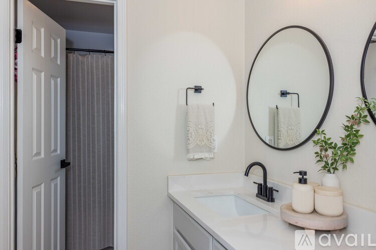 A bathroom with a white sink and two round mirrors.