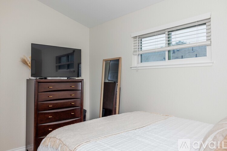 A bedroom with a bed, dresser, and a window with blinds.