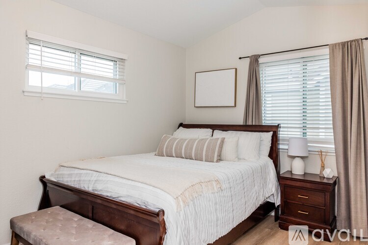 A bedroom with a large bed and a window with blinds.