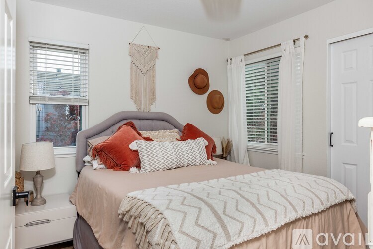 A bedroom with a large bed and a window with blinds.