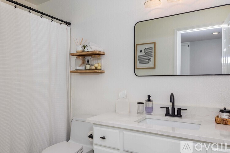 A white bathroom with a toilet, sink, and mirror.
