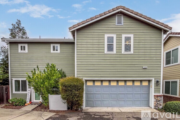 A two-story house with a garage door is for sale.