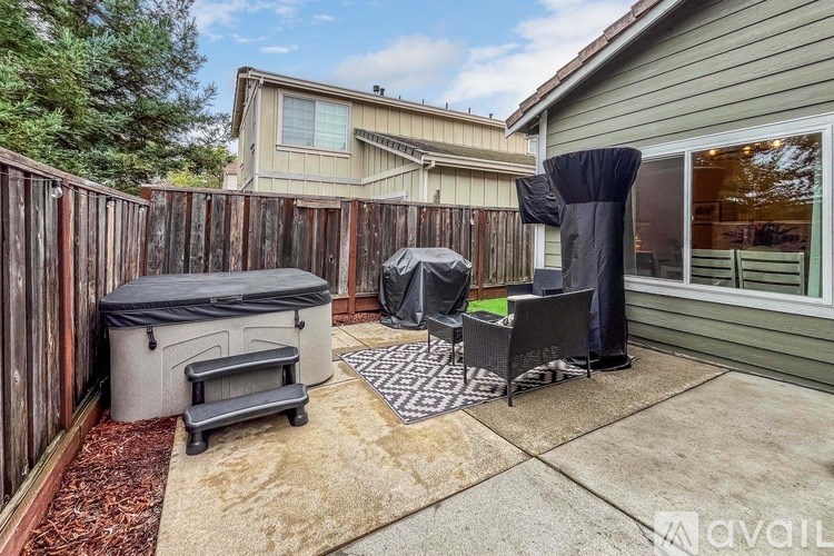 A backyard with a grill, patio furniture, and a trash bin.