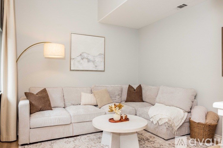 A living room with a white couch and a small table with a vase of flowers on it.