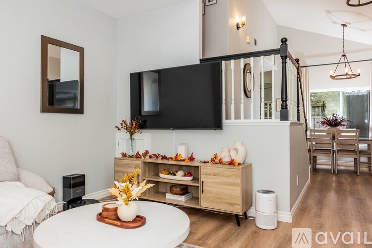 A living room with a white couch, a wooden coffee table, and a black television mounted on the wall.